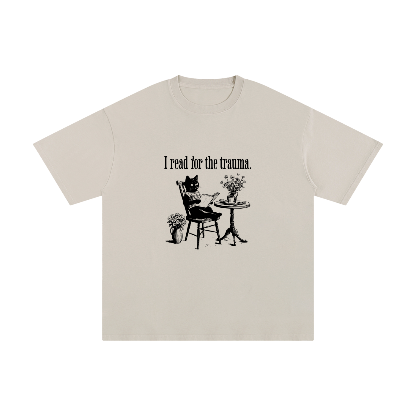 Beige t-shirt with a graphic of a cat reading a book and text 'I read for the trauma' on a white background.