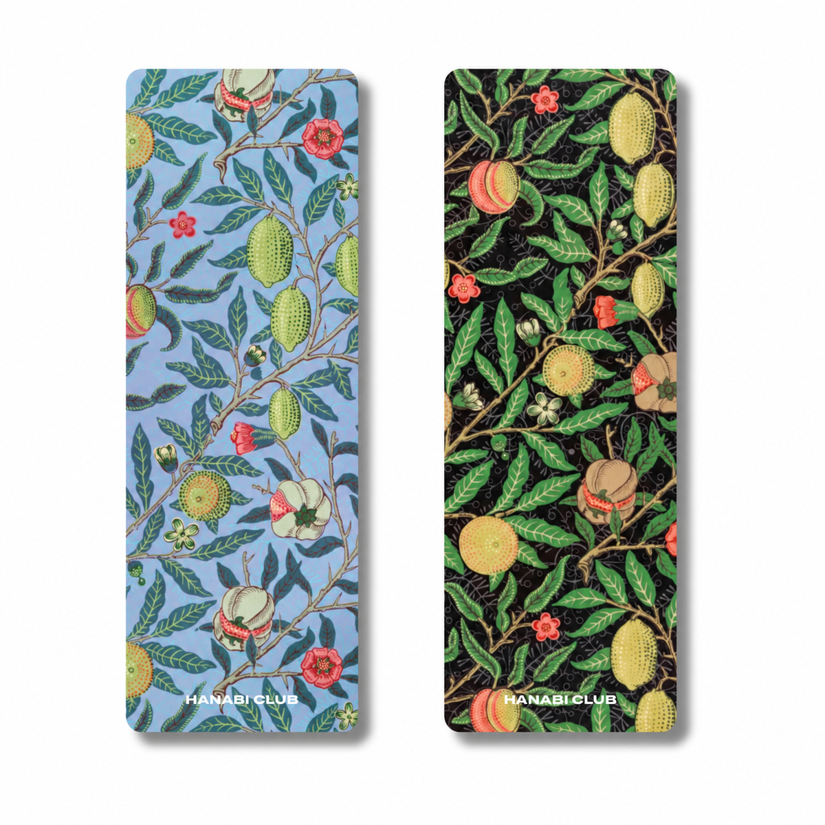 Two long rectangular printed items with rounded corners, shown side by side on a white background. The left has a light blue background with green leaves, yellow-orange fruits, and small red flowers; the right has a black background with the same botanical fruit pattern.
