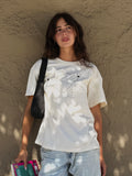 Model wearing the “Books and Wine” T-shirt with jeans while holding books outdoors.