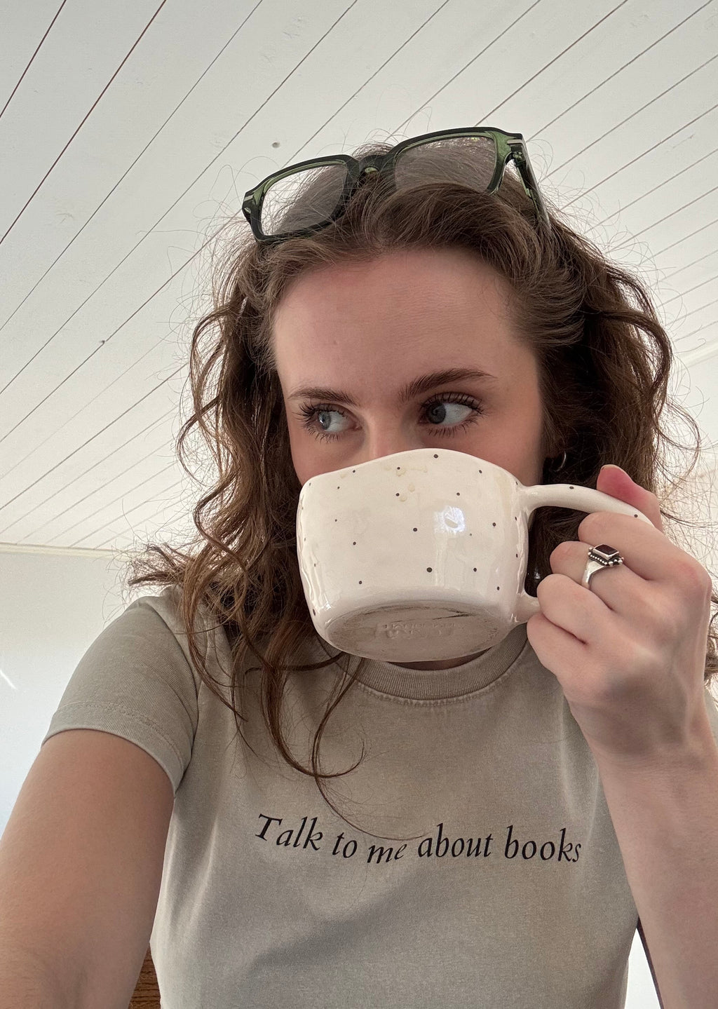 Model wearing the HANABI CLUB “Talk to me about books” ladies tee while holding a mug.