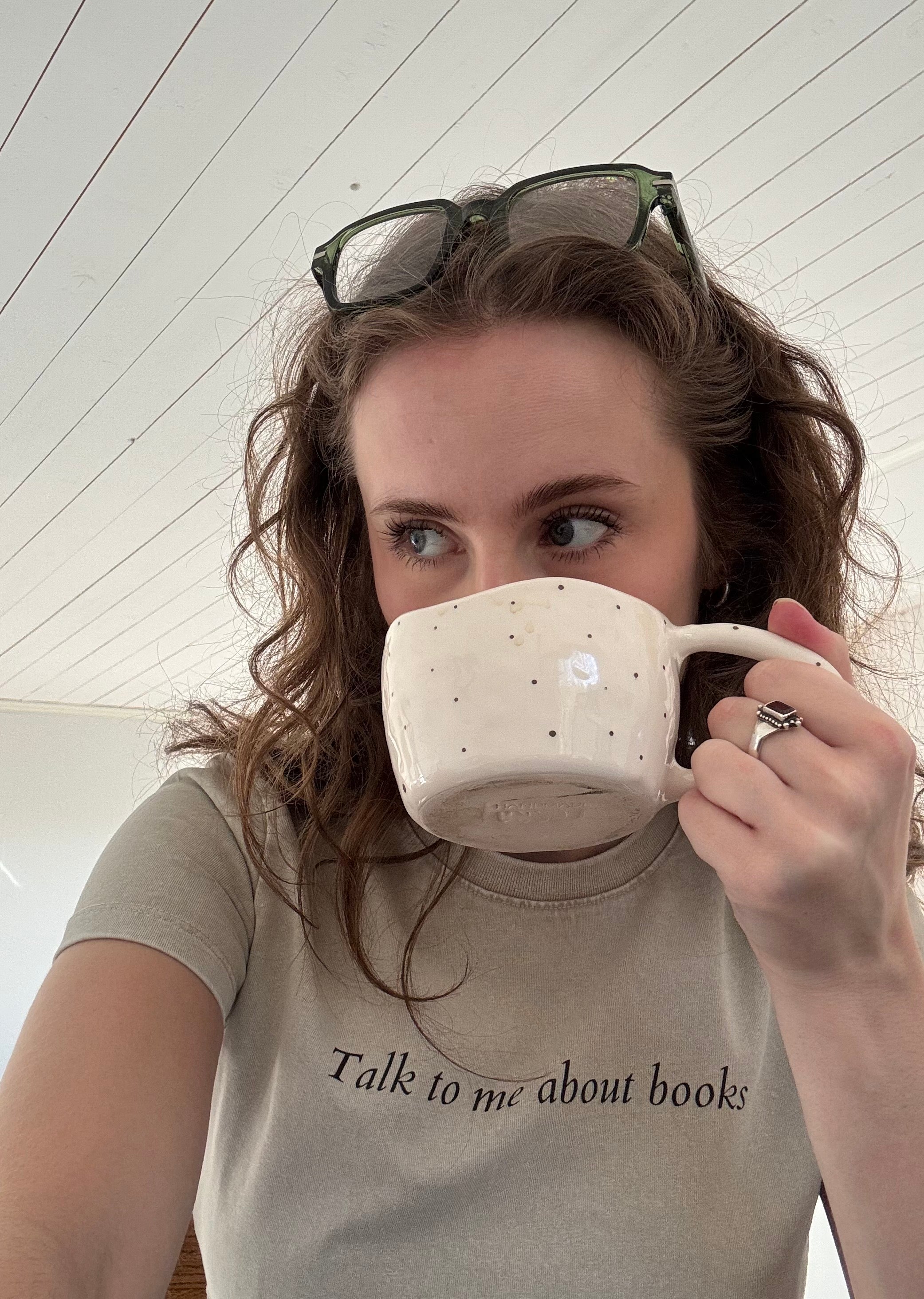 Model wearing the HANABI CLUB “Talk to me about books” ladies tee while holding a mug.