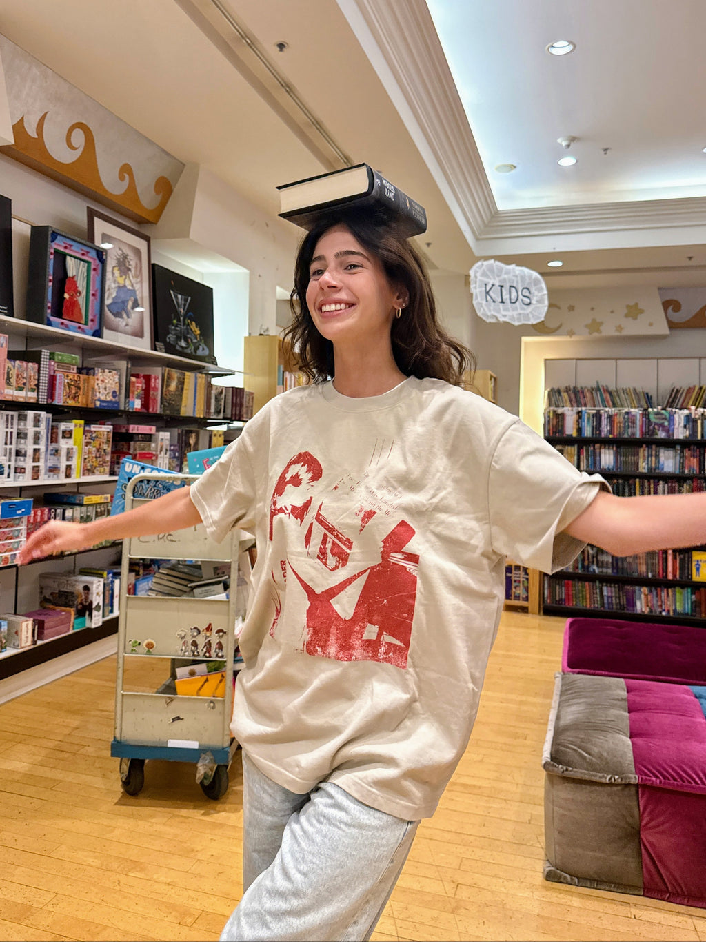 Model wearing the HANABI CLUB “The Reader” unisex T-shirt in a bookshop.