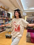 Model wearing the HANABI CLUB “The Reader” unisex T-shirt in a bookshop.