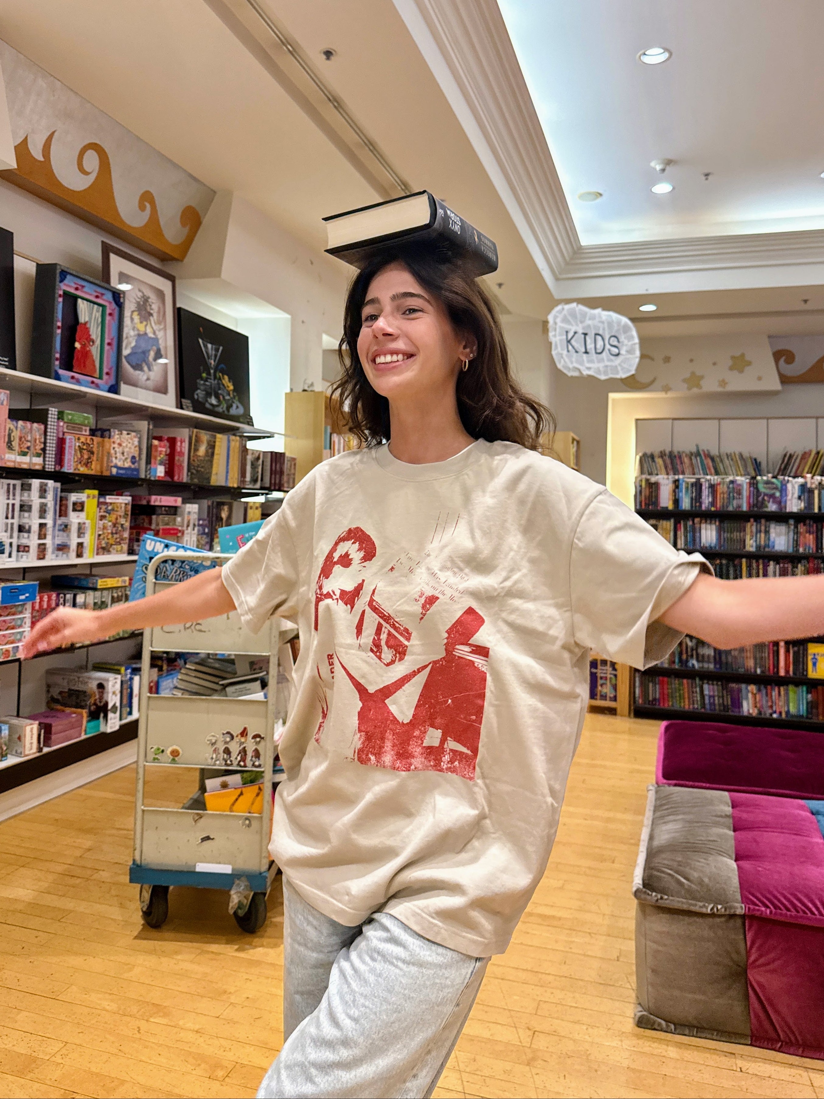 Model wearing the HANABI CLUB “The Reader” unisex T-shirt in a bookshop.