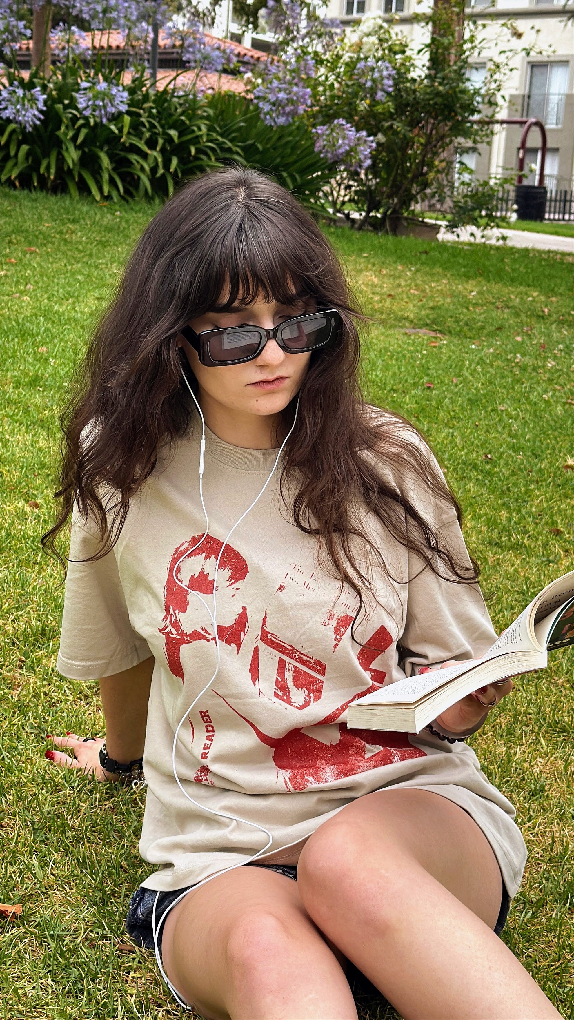 Model sitting in a park reading while wearing the “The Reader” unisex T-shirt.