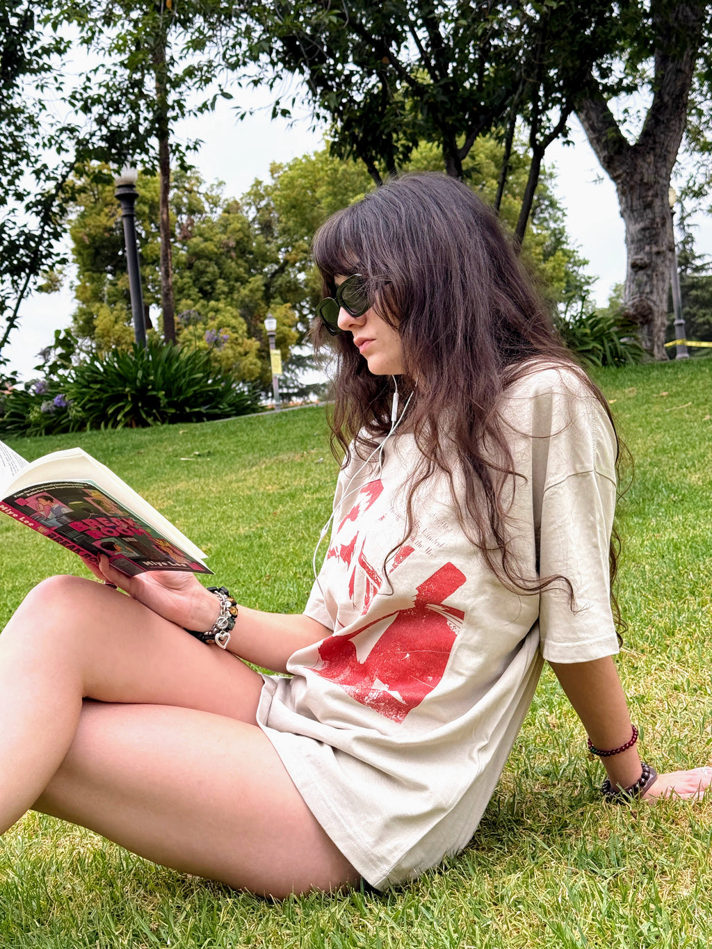 Model reading outdoors in the “The Reader” unisex T-shirt.