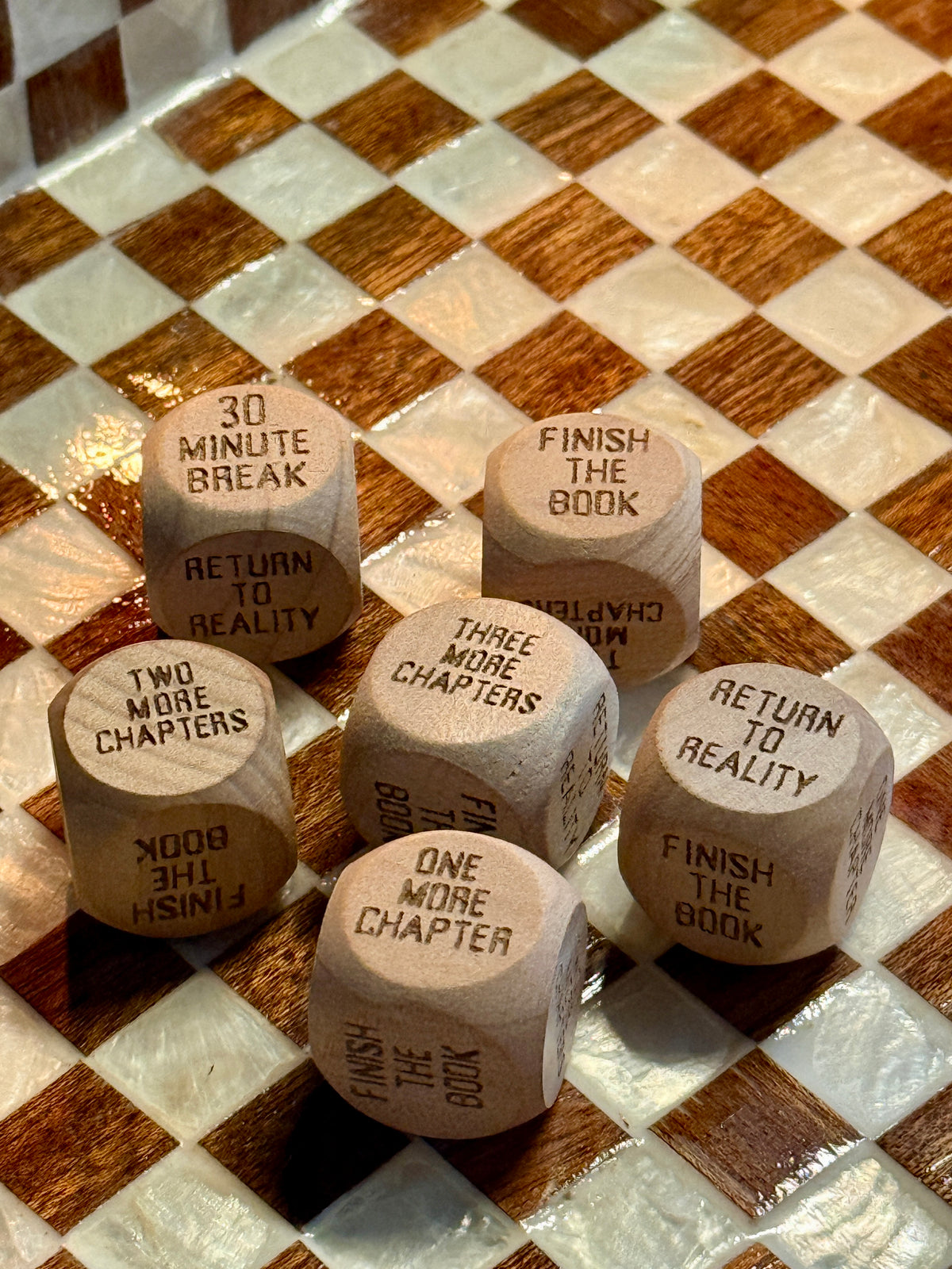 Six wooden HANABI CLUB Reading Decision Dice displaying different chapter challenges on a chequered tray.