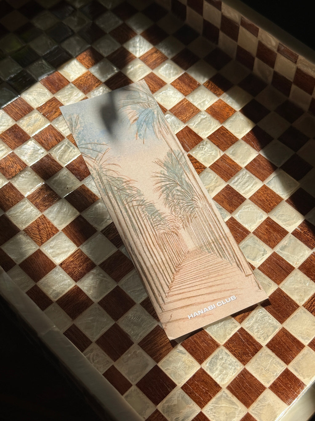 Under the Palms double-sided bookmark with pastel palm-lined walkway illustration