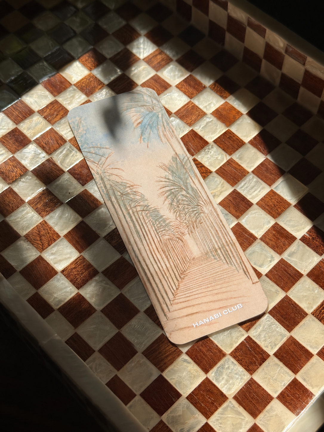 Under the Palms double-sided bookmark with pastel palm-lined walkway illustration